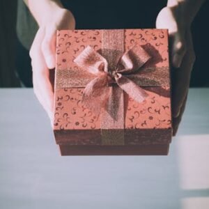 Hands presenting a beautifully wrapped gift box with a floral pattern, perfect for any celebration.